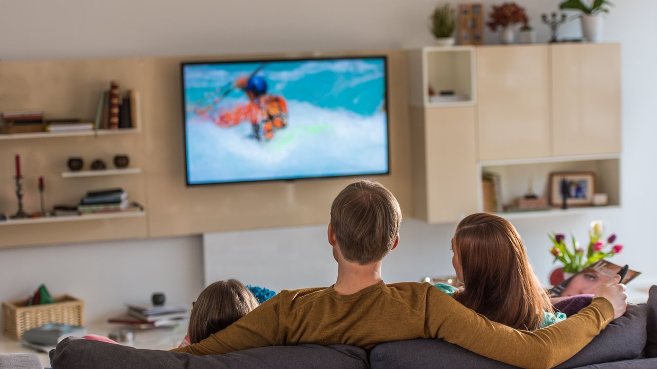 Familie schaut zusammen etwas im Fernseher an. 