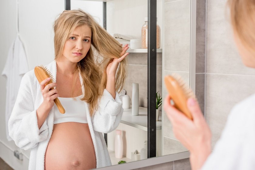 Schwangere Frau begutachtet ihre Haare.